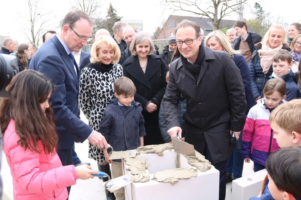 Bürgermeister Reiner Breuer und Baudezernent Christoph Hölters mauerten gemeinsam mit den Kindern deren Wünsche zusammen mit einer Tageszeitung und Münzen in den Grundstein ein.