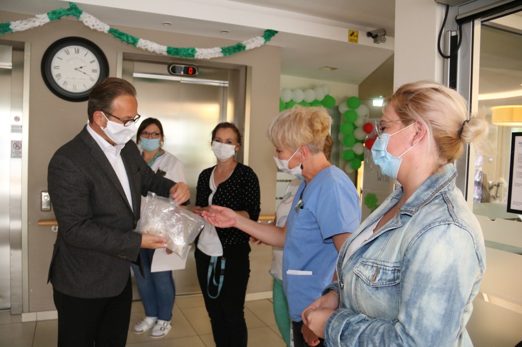 Bürgermeister Reiner Breuer verteilt Anstecknadeln mit dem Neusser Wappen an die Pflegekräfte.