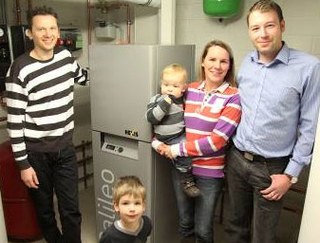 Innovative Zukunftstechnik, aber nicht größer als eine Kühl-Gefrier-Kombination: Gregor und Tamara Mönks (rechts im Bild) und Familien-nachwuchs Maximilian und Jonathan freuen sich über ihr neues kompak-tes „Kellerkraftwerk“, das Sanitär- und Heizungsexperte Alexander Sta-mos (links) und sein Team erfolgreich installiert haben. 