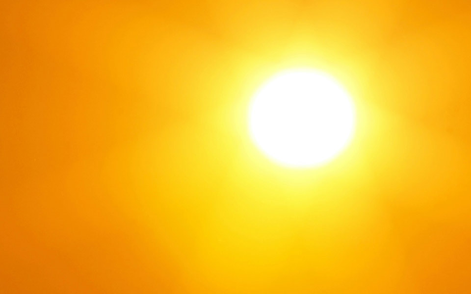 Unscharfe Aufnahme eines wolkenlosen Himmels mit stark überstrahlender Sonne zur Dämmerungszeit