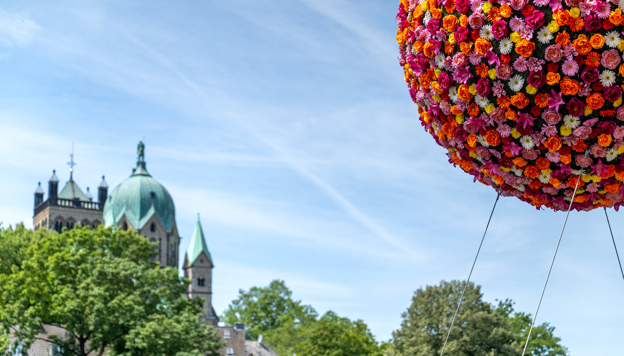 Stimmungsvolles Foto mit einem der beiden Flowerballs im Neusser Hafen und dem Qurinus-Münster unscharf im Hintergrund