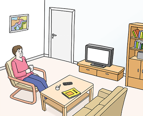 Eine Frau sitzt im Wohnzimmer.