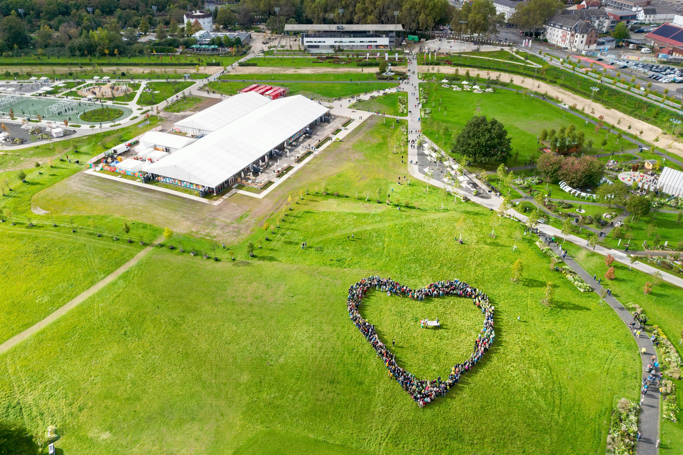 Drohnenfoto: Hunderte Menschen Bilden ein Herz auf dem Gelände der Landesgartenschau.