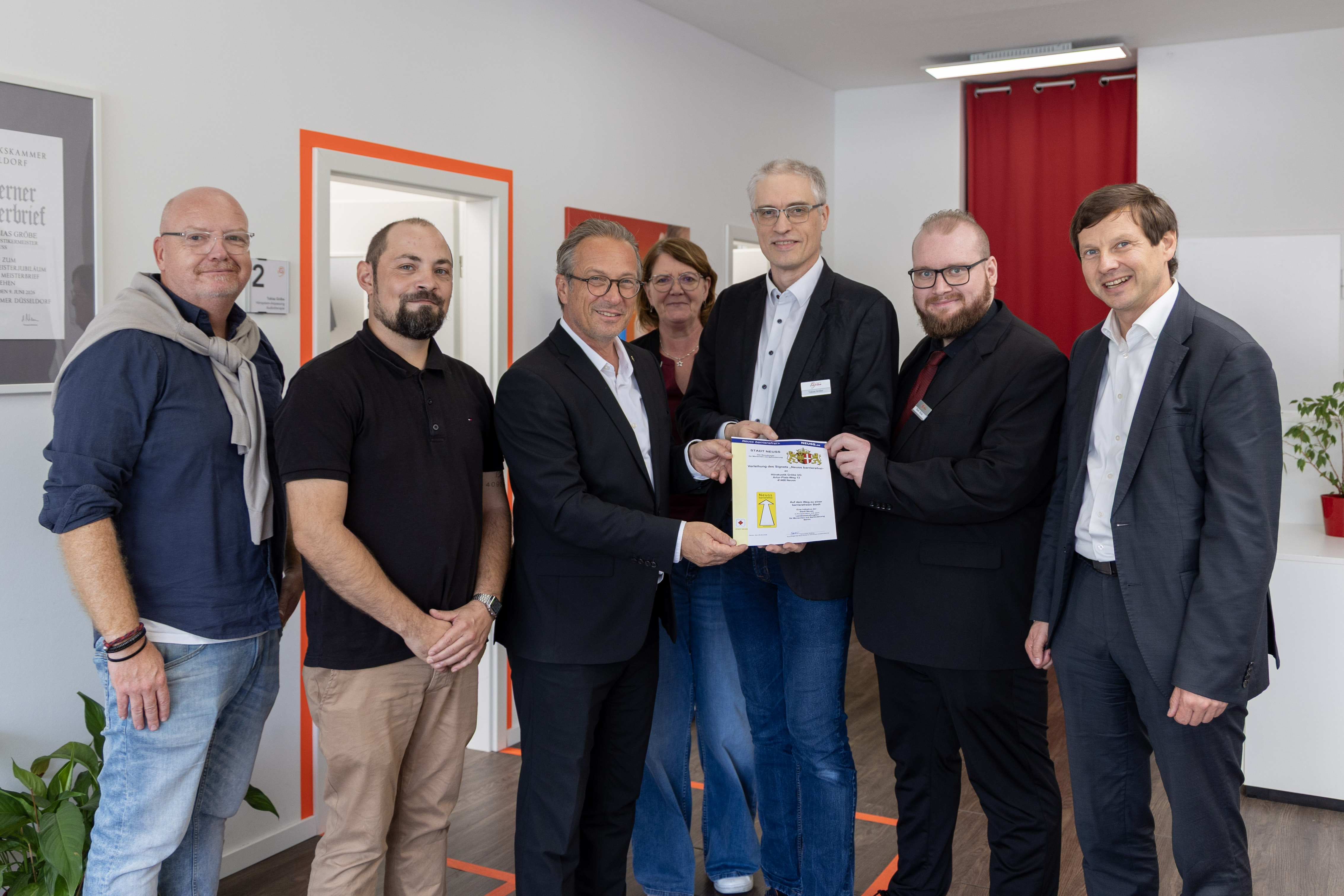 Eine Gruppe von Menschen mit einer Urkunde schaut in die Kamera
