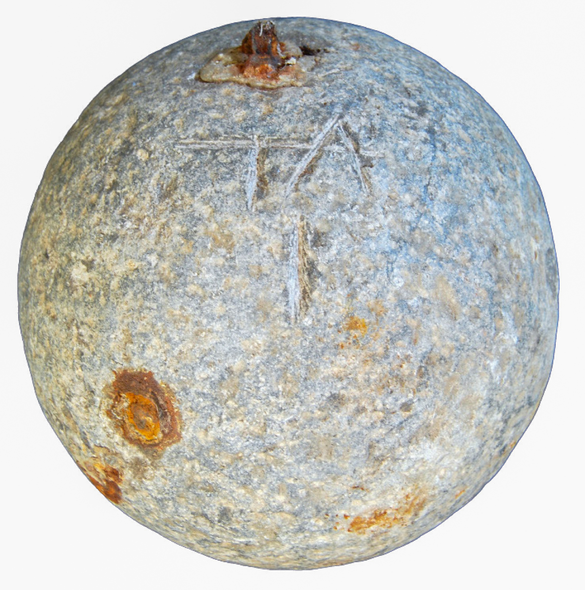 Fotografie einer grauen Kanonenkugel, an mehreren Stellen durch Rost verfärbt.