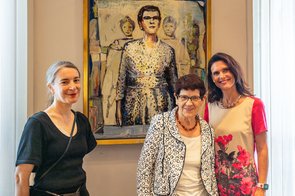 Frau Süssmuth steht gemeinsam mit der Künstlerin und der Beigeordneten vor dem Portraitgemälde und lächelt in die Kamera.