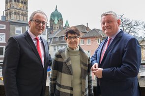 Frau Süssmuth steht gemeinsam mit den Herren Breuer und Gröhe auf dem Neusser Rathausbalkon. Im Hintergrund ist das Quirinus-Münster zu sehen.
