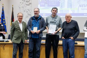 Eine Gruppe von Menschen wird im Ratssaal der Stadt Neuss ausgezeichnet und hält eine Urkunde in die Kamera.