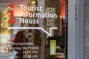 Ein Logo mit der Aufschrift "Neuss barrierefrei" auf einer Schaufensterscheibe.