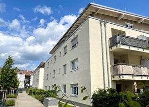 Mehrere Mehrfamilienhäuser mit Balkonen an einem Gehweg.