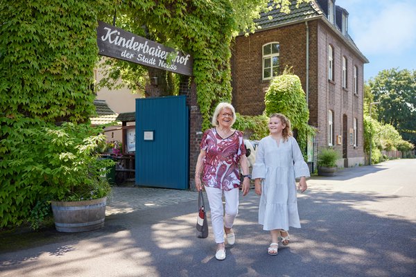 Oma und Enkelin kommen zu Fuss aus dem Kinderbauernhof