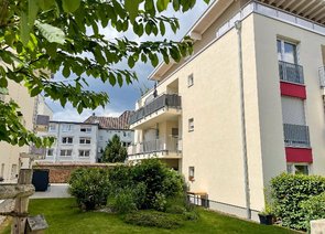 Zwischenbereich eines Wohngebäudekomplexes mit Balkonen und einer Grünfläche.