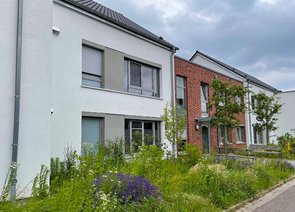 Moderne Wohnhäuser mit einer Fassade aus weißem Putz und Ziegeln sowie mit buntem Vorgarten.