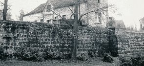 Schwarz-Weiß-Foto eines Abschnitts der Stadtmauer. Dahinter ist ein Wohnhaus zu erkennen.