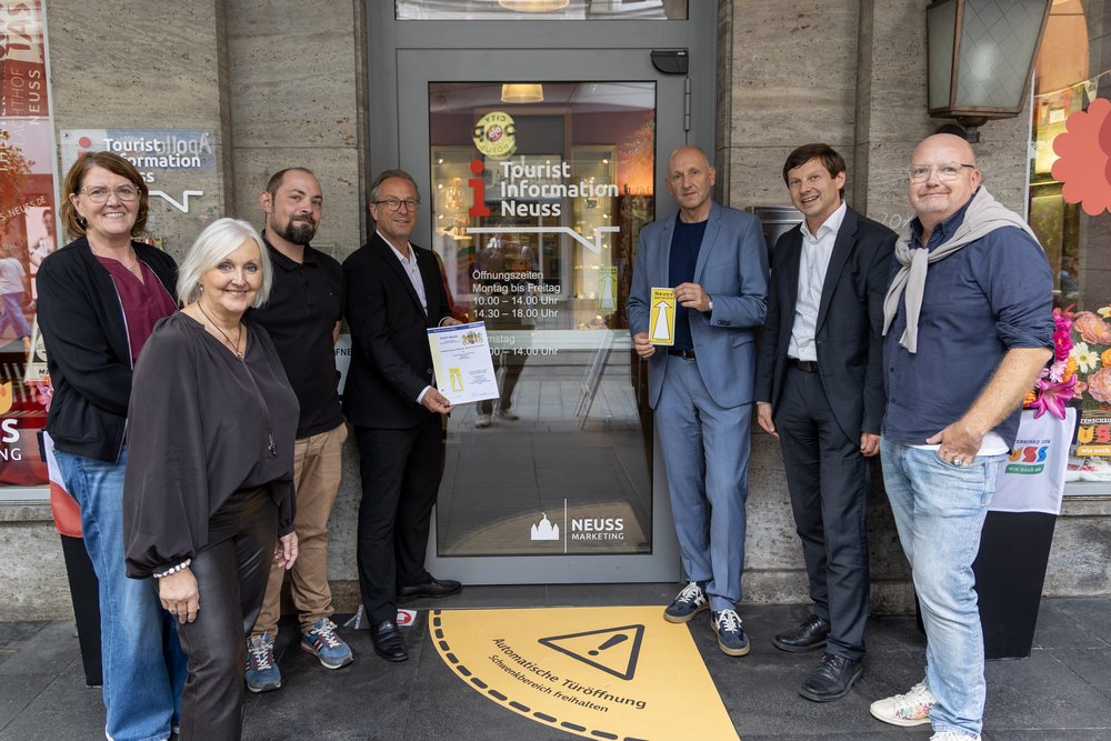 Eine Gruppe von Menschen schaut in die Kamera und präsentiert eine Urkunde.