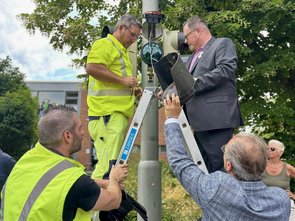 Eine Gruppe von Menschen montiert auf einer Leite eine neue Fußgängerampel.