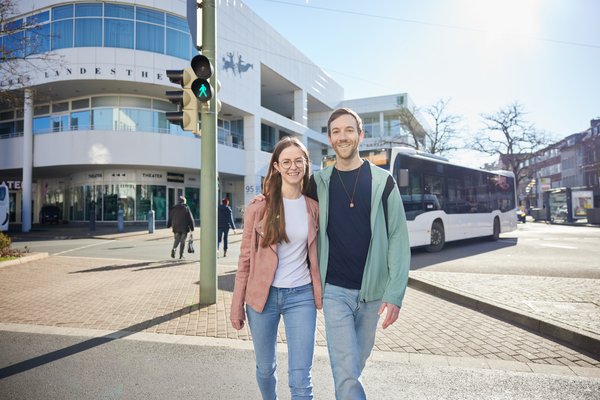 Zu Fuss Gehende queren die Ampel vor dem Landestheater