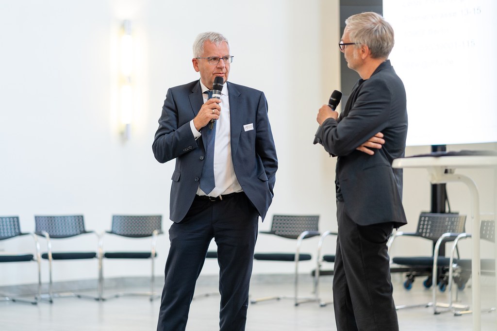 Zwei Konferenz-Teilnehmer tauschen sich auf der Bühne des Zeughauses aus.